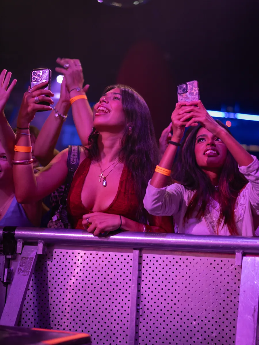 The crowd filming the stage on their phones under purple light